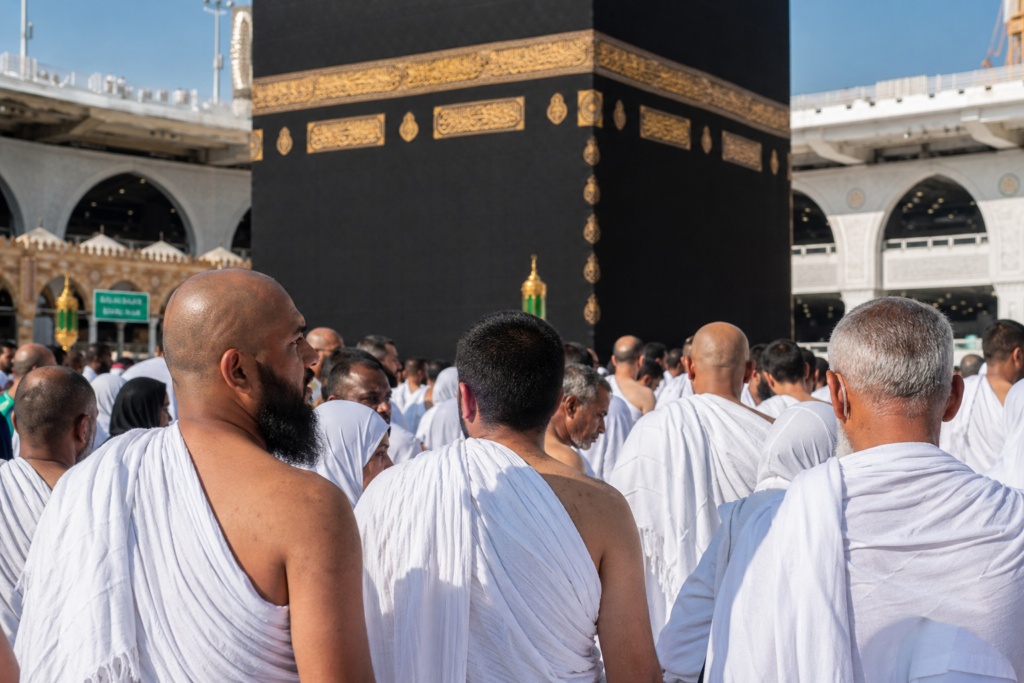 Ilustrasi jamaah di depan Ka'bah untuk menjelaskan perbedaan haji dan umroh secara lengkap.