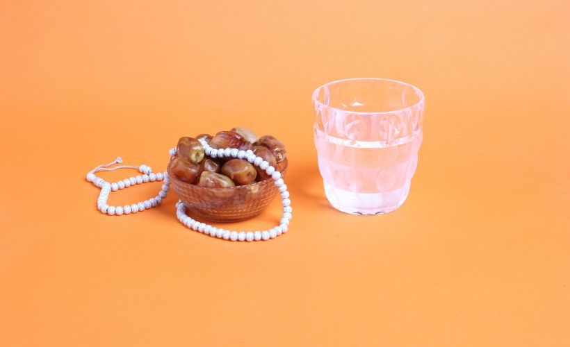 a-glass-of-water-next-to-a-beaded-bracelet